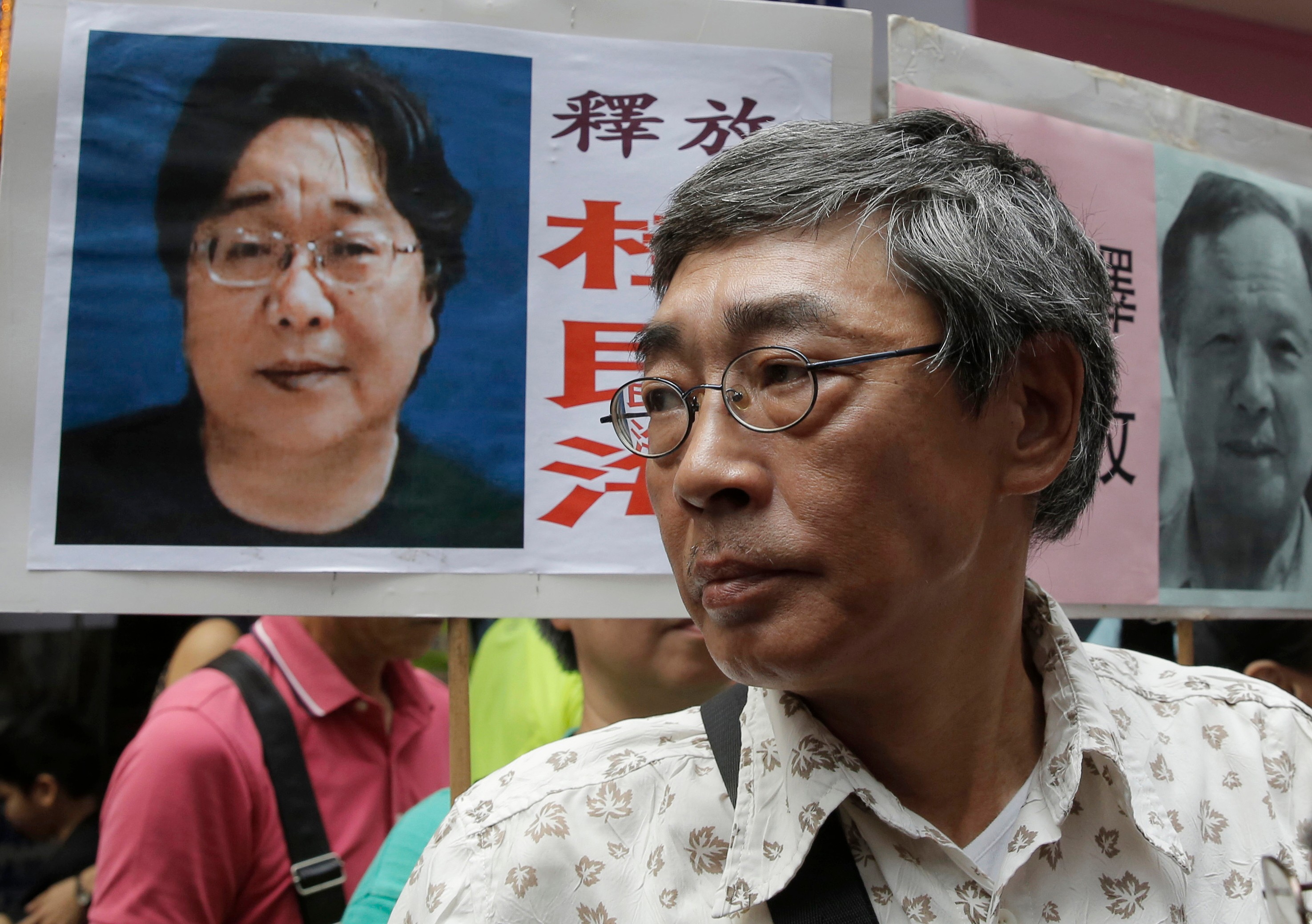 FILE - Freed Hong Kong bookseller Lam Wing-kee stands next to a placard with a picture of missing bookseller Gui Minhai, left, in front of his book store during a march in Hong Kong on June 18, 2016.